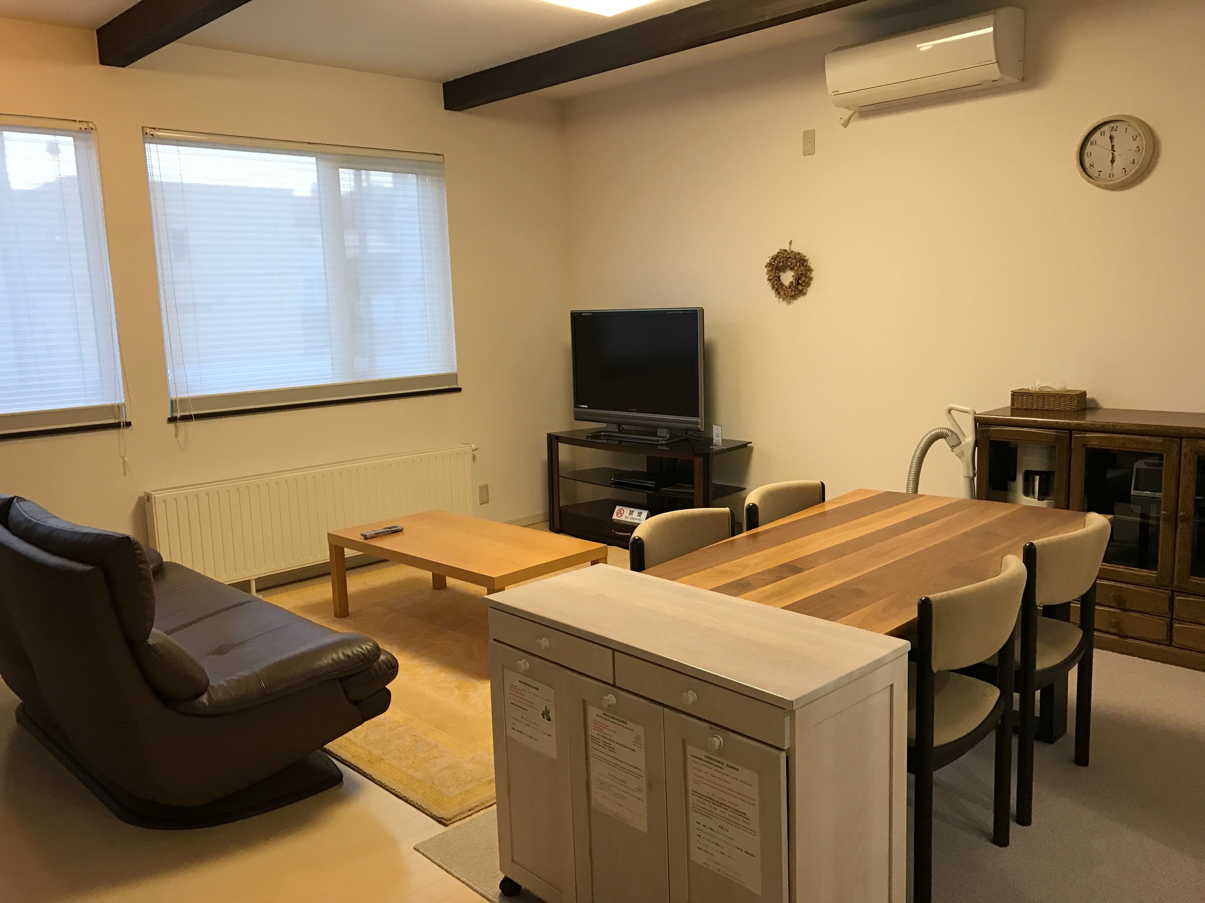 Un salon avec un canapé, une table en bois, un téléviseur et un meuble.