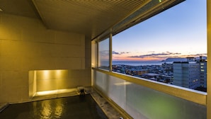 Una habitación con un amplio ventanal que da a una vista urbana al anochecer.
