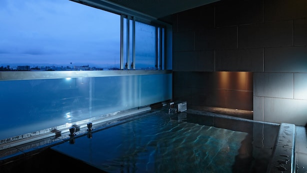 Una piscina interior moderna con vistas a la ciudad, grandes ventanales y un diseño elegante.