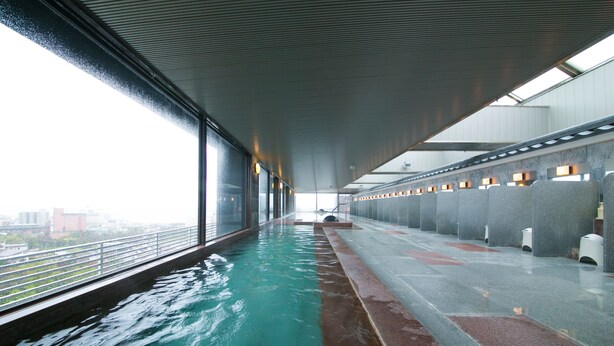 An indoor swimming pool with a view of the city through large windows. - Bourou NOGUCHI Hakodate Ryokan (Hakodate)