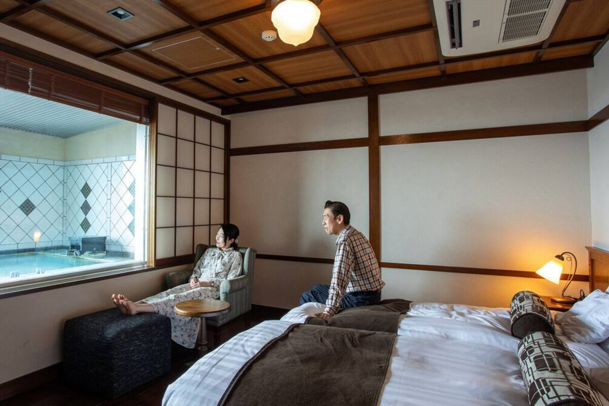 Una habitación con una cama, una ventana con vistas, una mesita y una silla.
