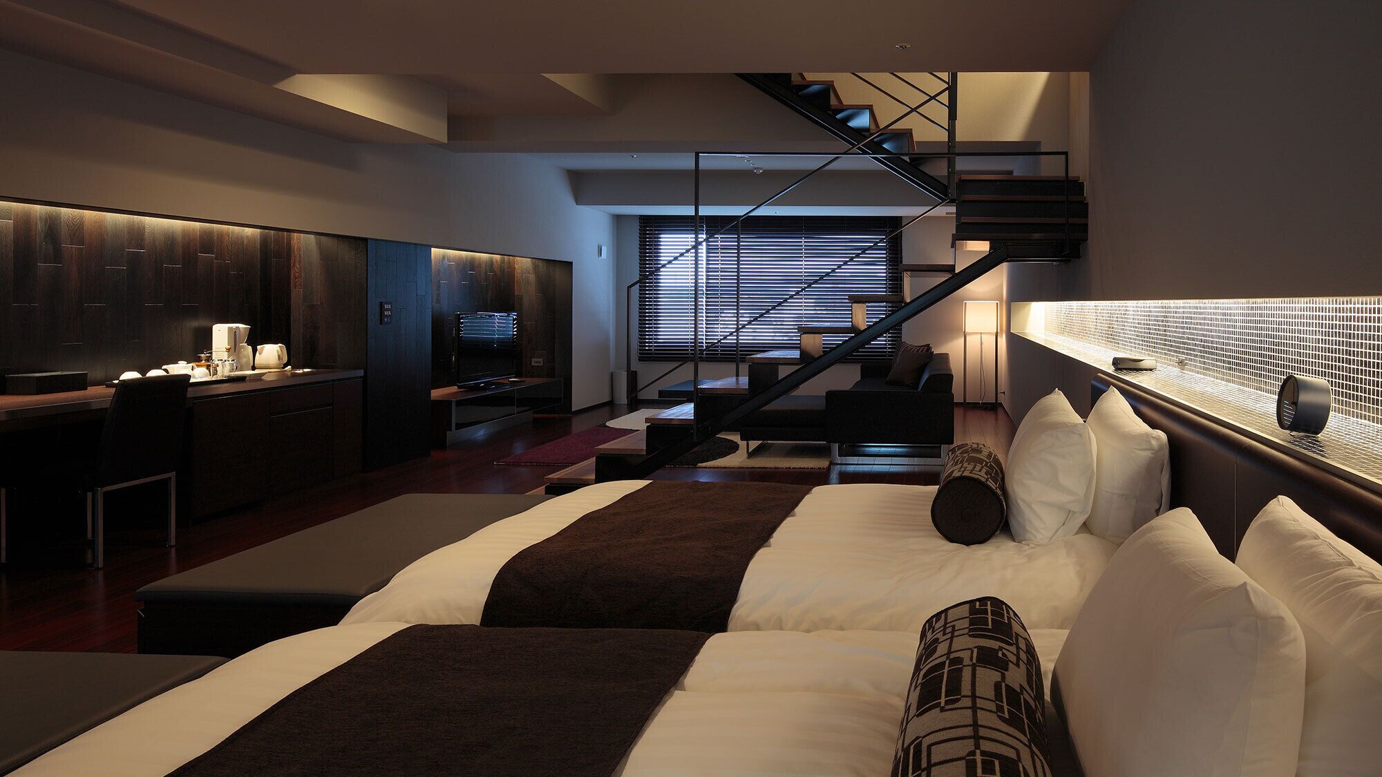 Un dormitorio moderno con una cama grande, una escalera y una zona de cocina.