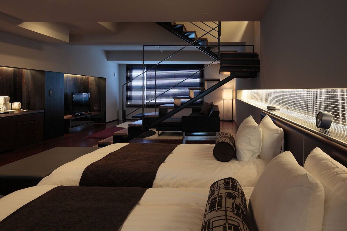 Un dormitorio moderno con una cama grande, una escalera y una zona de cocina.