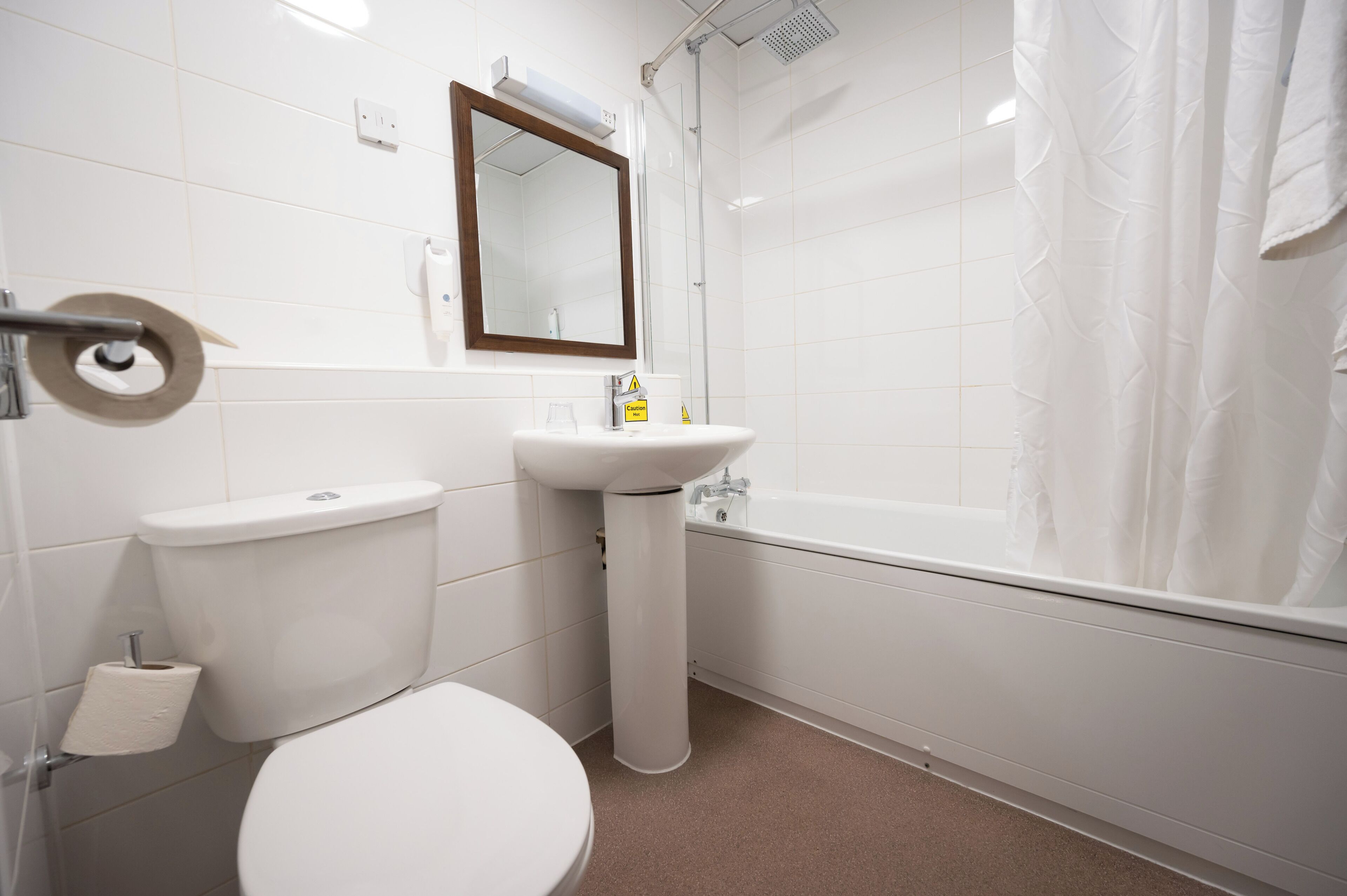 A bathroom with a toilet, sink, mirror, and shower curtain.