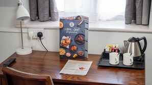 A hotel room with a wooden desk, a lamp, a menu, two mugs, and a kettle. - Cocked Hat Hotel by Greene Kings Inns (Coventry)