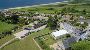 An aerial view of a coastal village with houses, a beach, and a large tent-like structure. - The Manor Hotel (Dorchester)
