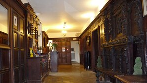 A hallway with stone flooring, wooden paneling, and a chandelier. - The Manor Hotel (Dorchester)