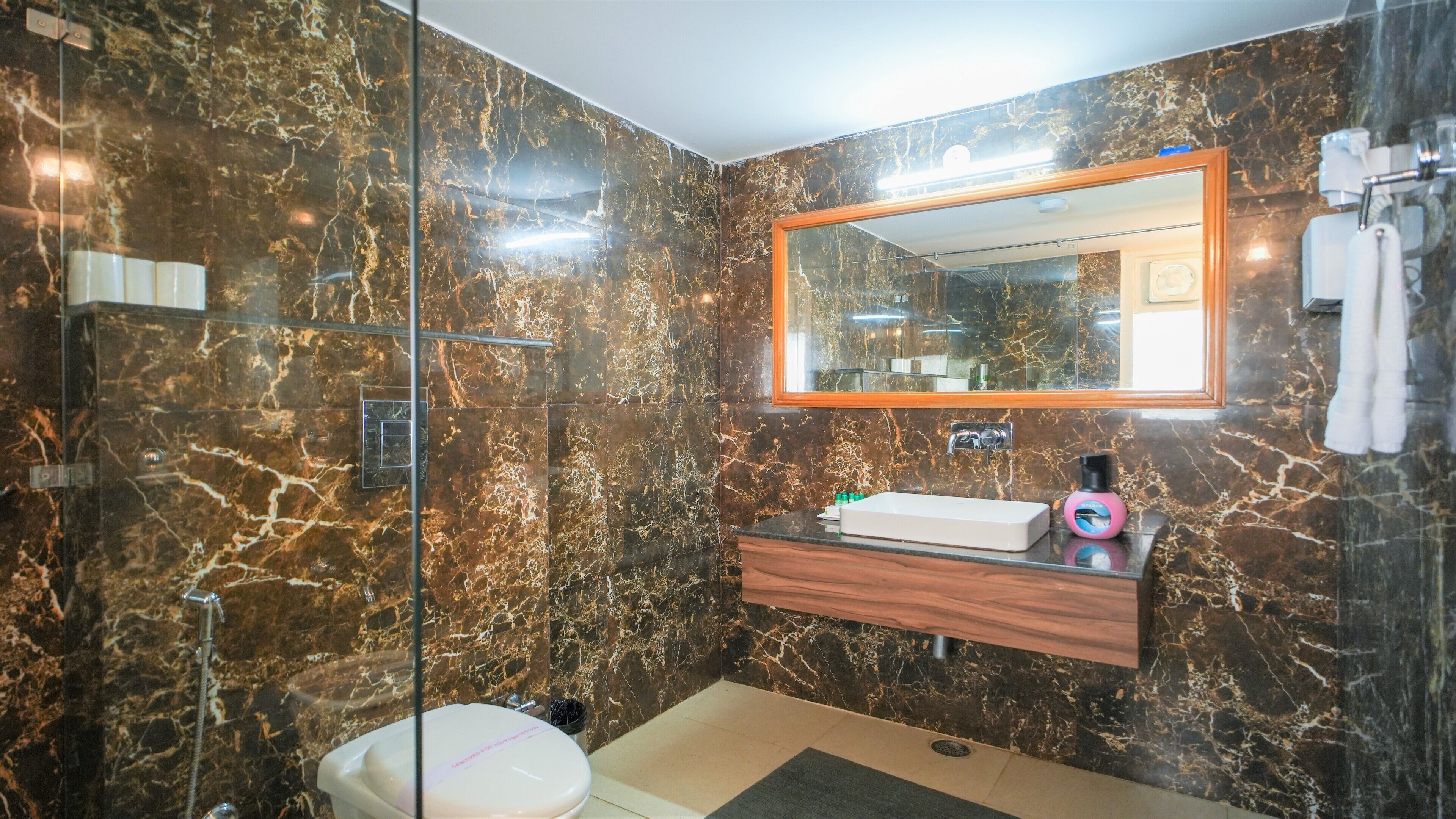 A bathroom with a glass shower enclosure, a toilet, a sink with a mirror above, and a towel rack.