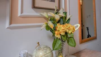 A wall-mounted light fixture, a framed picture, a mirror, a vase with flowers, a globe, and a tissue box.
