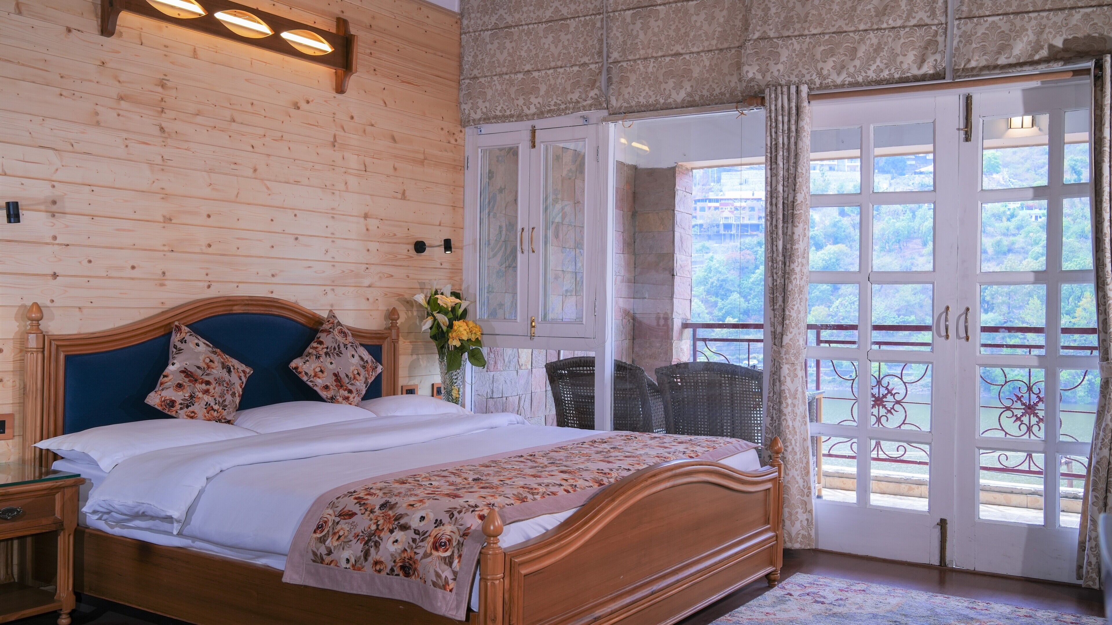 Une pièce aux murs lambrissés, avec un lit, une chaise et une vue sur l’extérieur, visible à travers une porte vitrée.