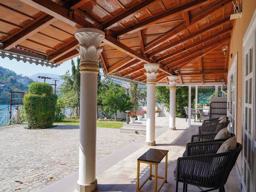 Um espaço ao ar livre coberto com colunas, móveis de vime e vista para um lago.