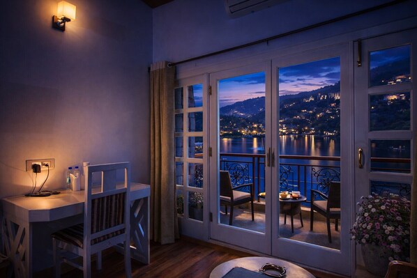 A balcony with a view of a lake and city lights at night. - Neelesh Inn - Luxury Lake View Hotel With Swimming Pool On Bhimtal Lake (Nainital)