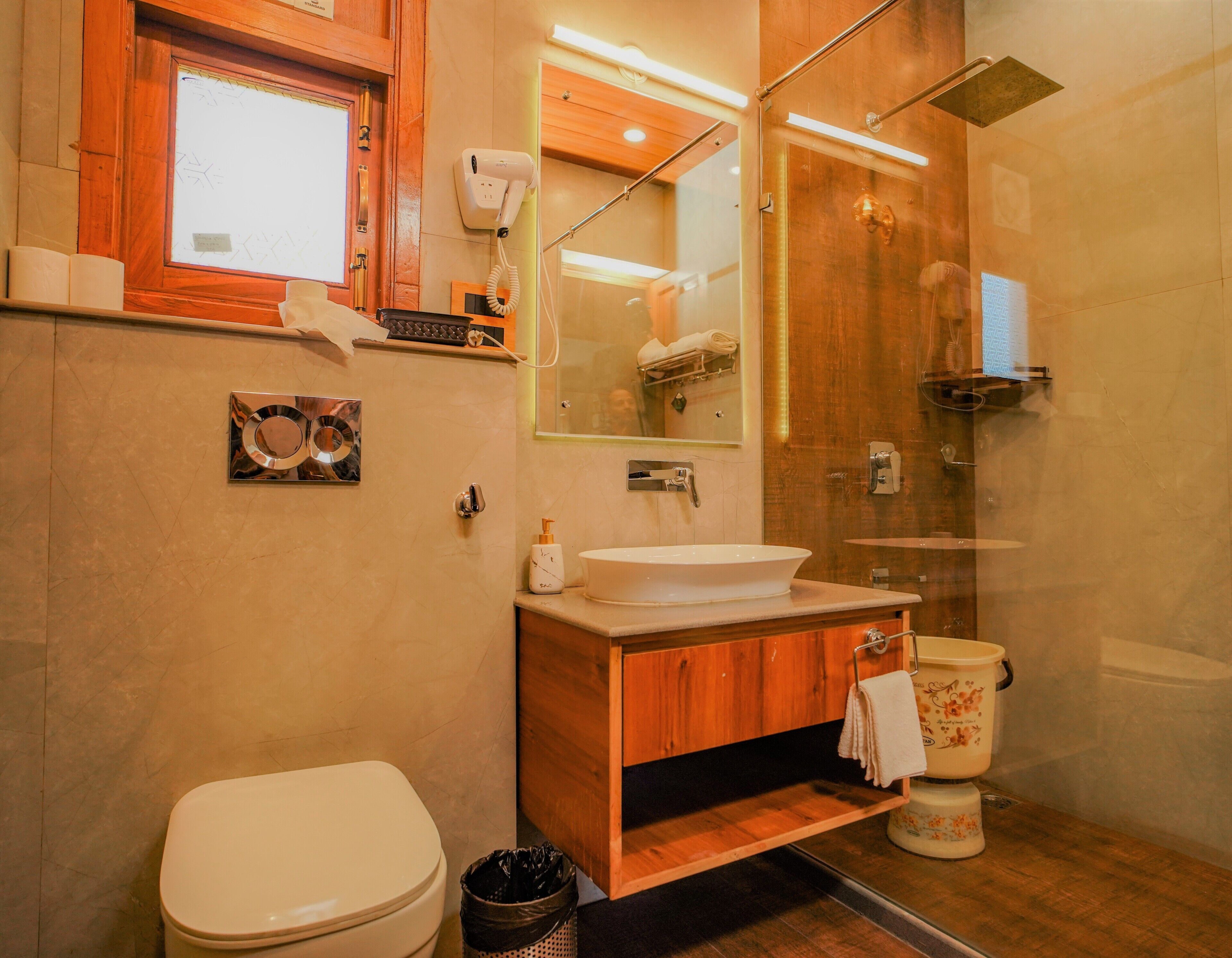 A bathroom with a toilet, sink, mirror, and shower.