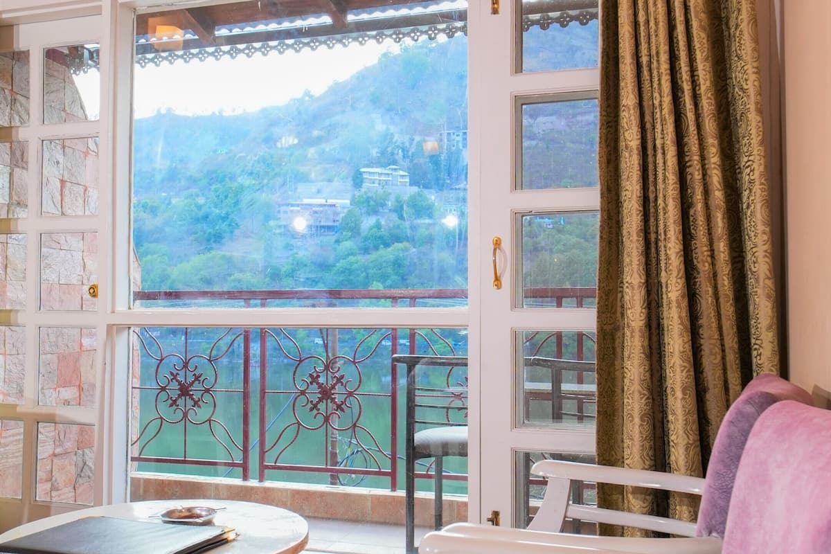 A room with a balcony, a sofa, a table, and an air conditioning unit.