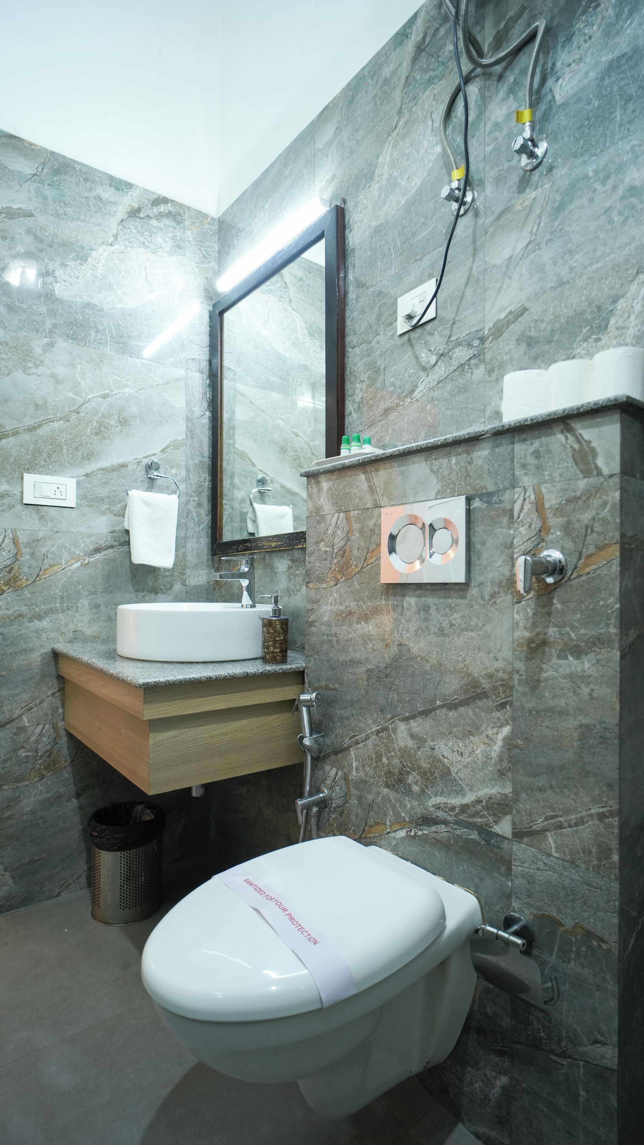 Une salle de bain avec un mur en marbre, un lavabo, des toilettes, un miroir et une douche.