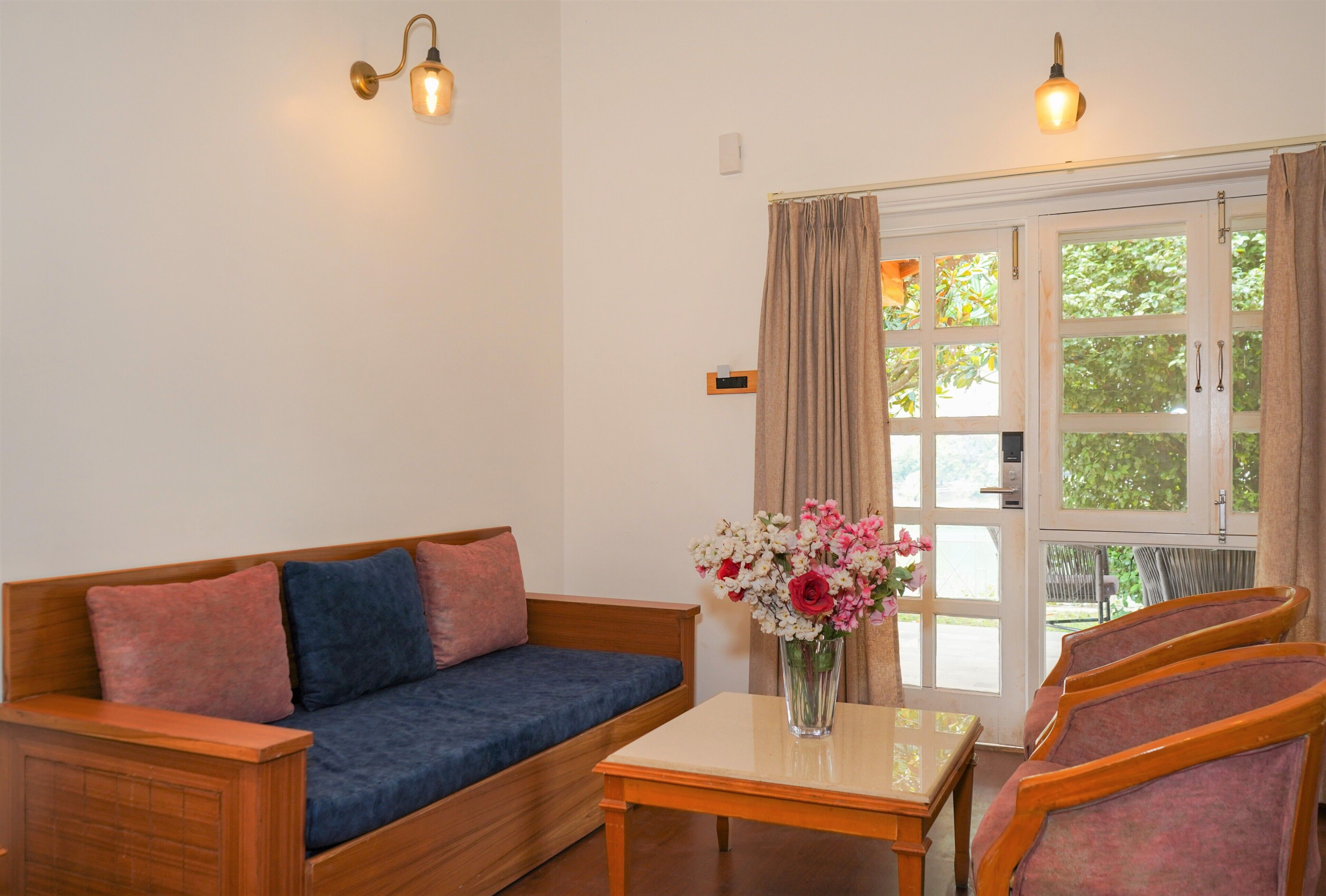 Ein Zimmer mit einer Holzdavonia, einem kleinen Tisch mit Blumenvase und einem Fenster mit Vorhängen.