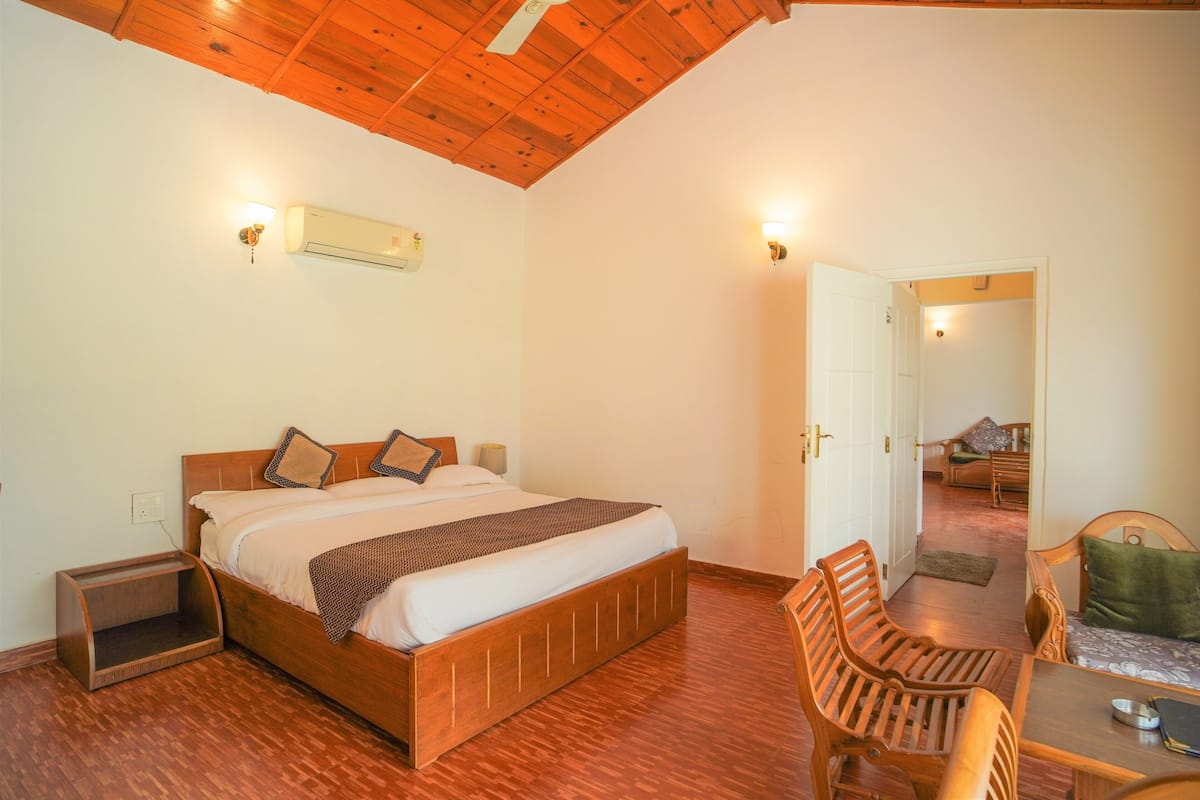 A bedroom with a wooden bed, a nightstand, a chair, and a table.