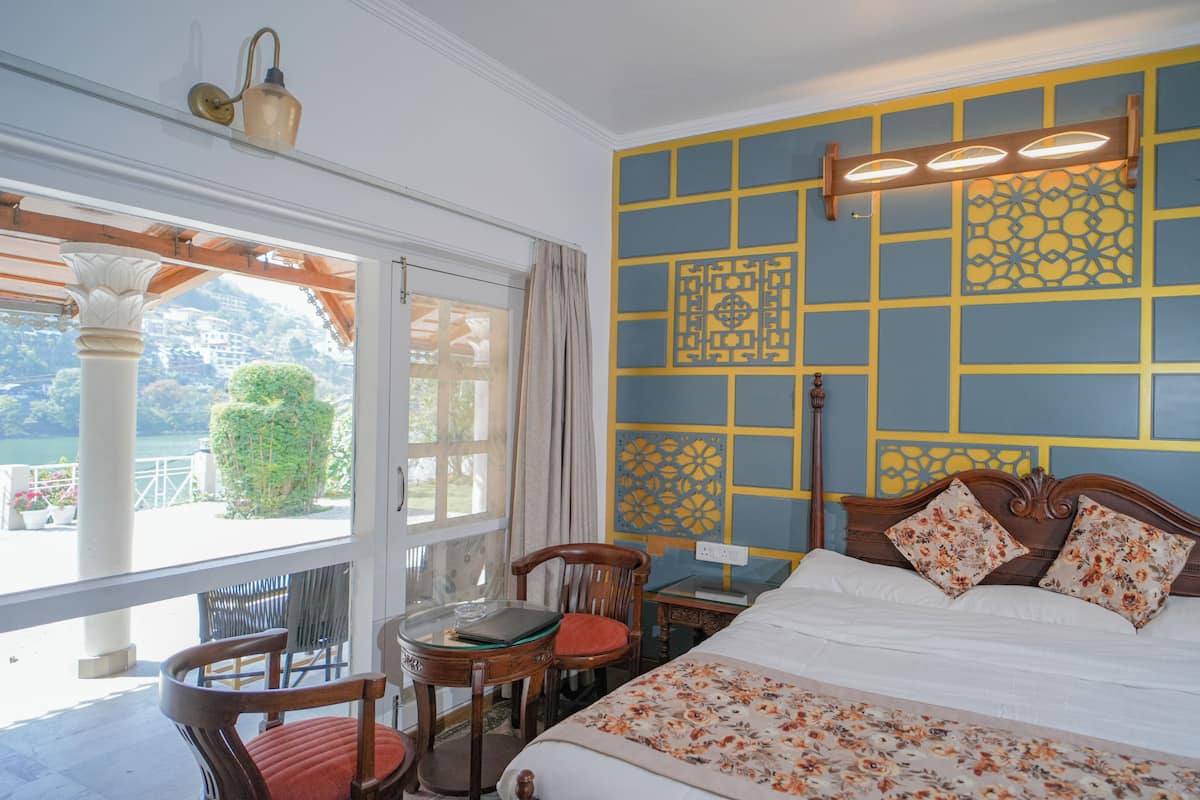 A hotel room with a bed, a table, chairs, and a view of the outdoors.