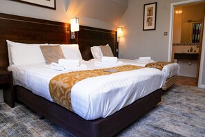 A hotel room with a large bed, two bedside tables, a nightstand, a mirror, and a bathroom visible through an open door. - New Wilmington Hotel (Eastbourne)