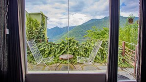 A balcony with two white chairs and a small table, overlooking a lush green landscape with mountains in the background. - Seclude Ramgarh, Cliff's Edge (Kosiyakutoli)