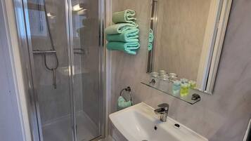 A modern bathroom with a glass shower enclosure, a white sink, and a mirror with a light above it.