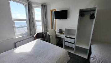 Habitación de hotel con una cama, un escritorio con silla, un televisor y un armario.