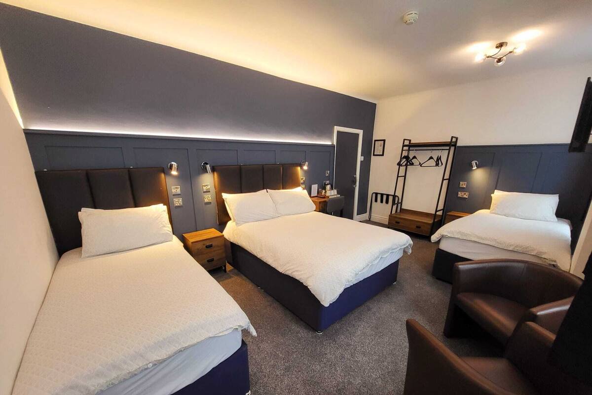 Ett hotellrum med tre sängar, ett skrivbord och en stol.