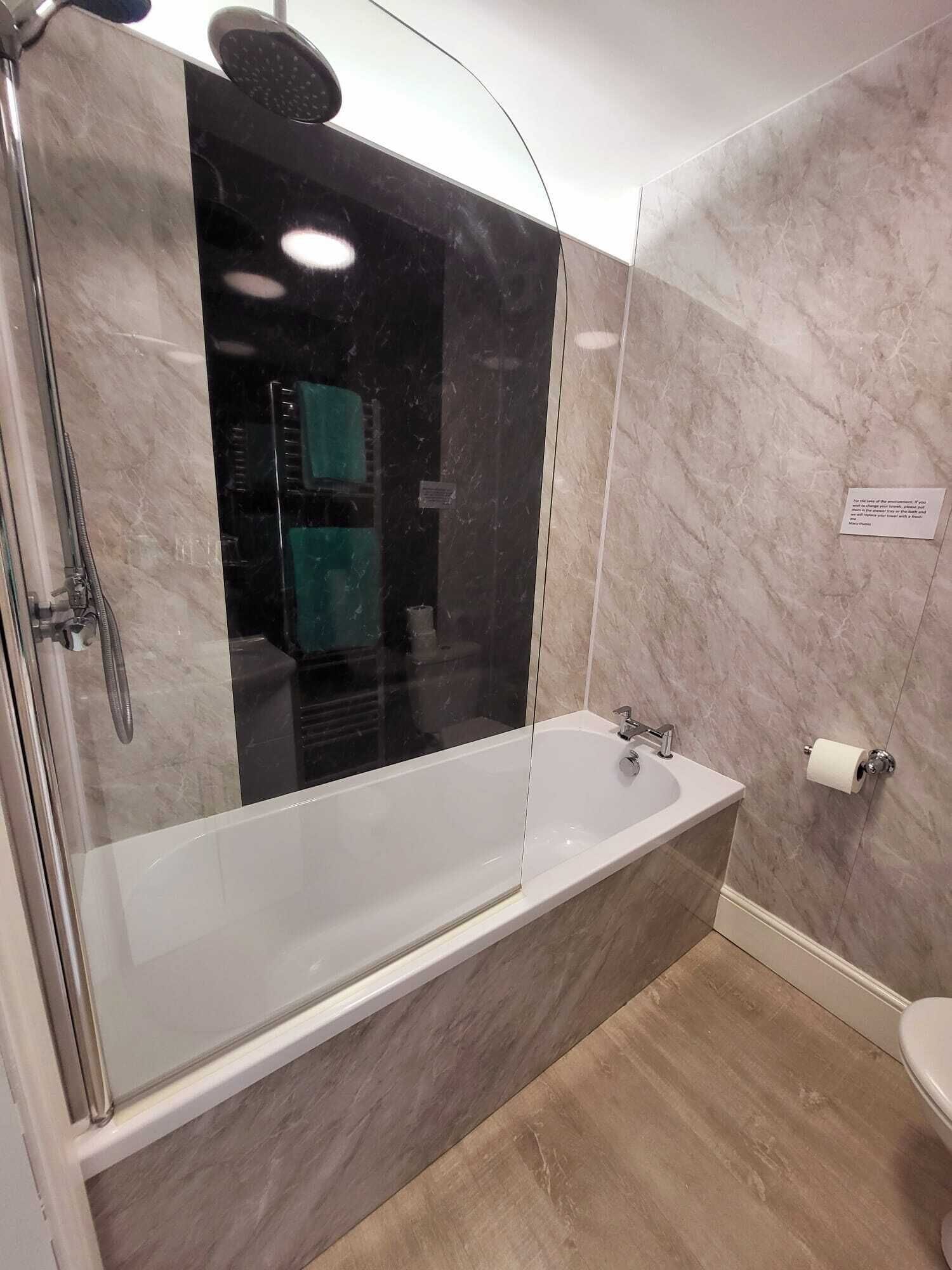 A modern bathroom with a glass-enclosed shower, a freestanding bathtub, and a toilet.