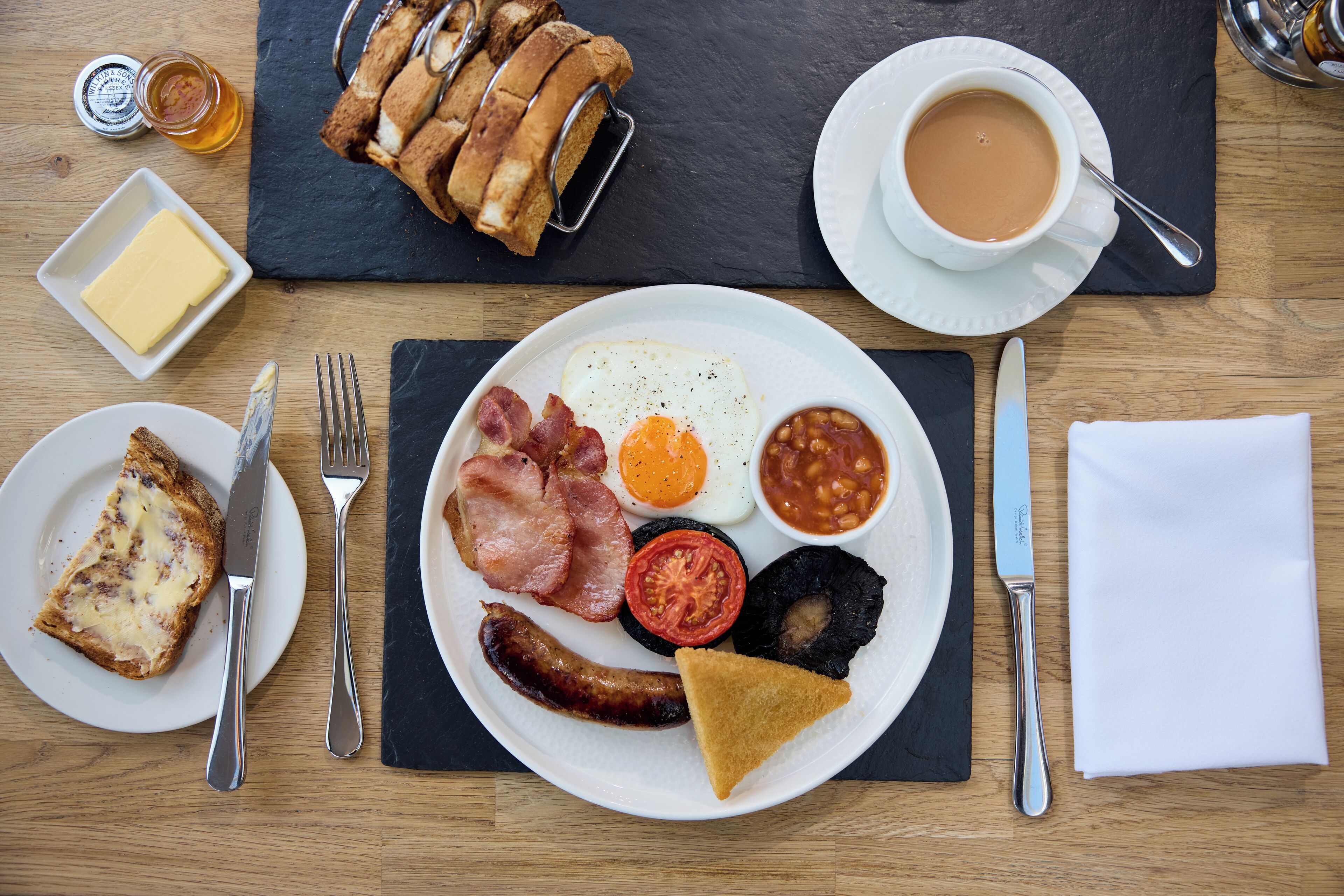 A breakfast plate with eggs, bacon, beans, tomato, and toast.