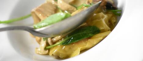 A white plate with a spoonful of noodles, green vegetables, and a piece of meat.