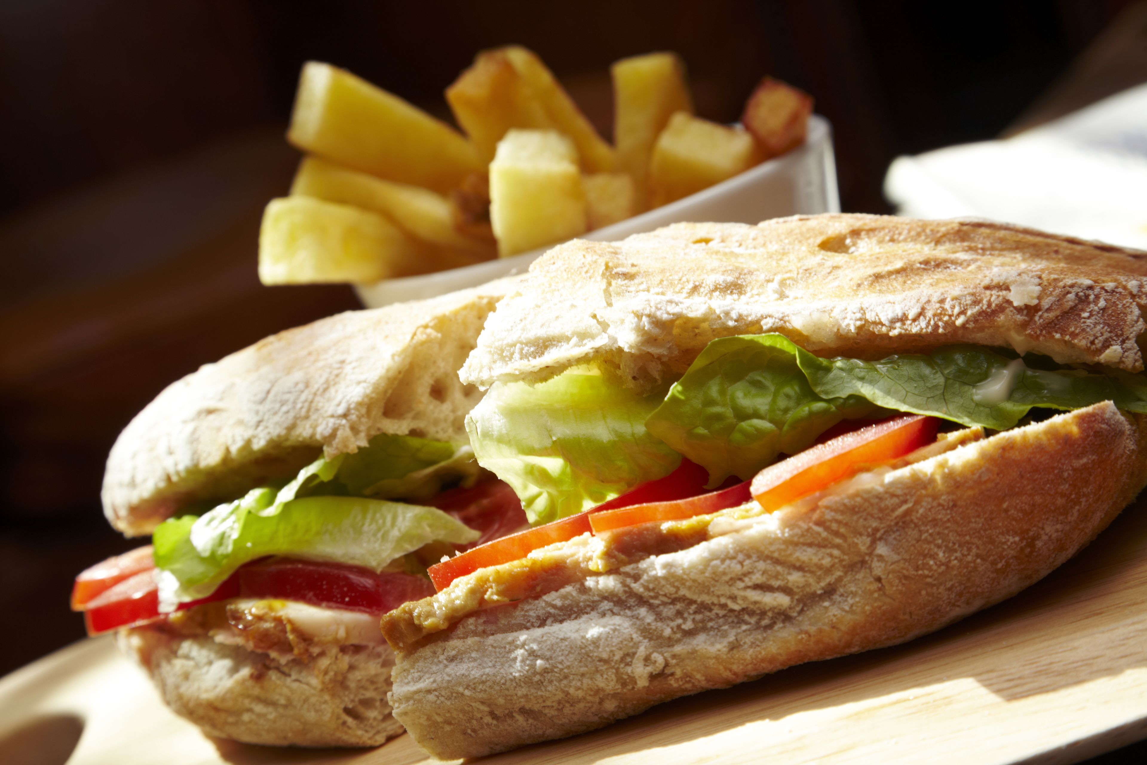 Un sandwich garni de laitue, de tomates et d’autres ingrédients, accompagné d’une portion de frites.