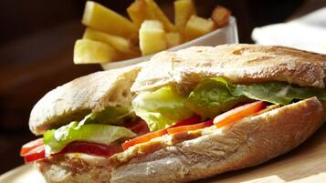 Un sandwich garni de laitue, de tomates et d’autres ingrédients, accompagné d’une portion de frites.
