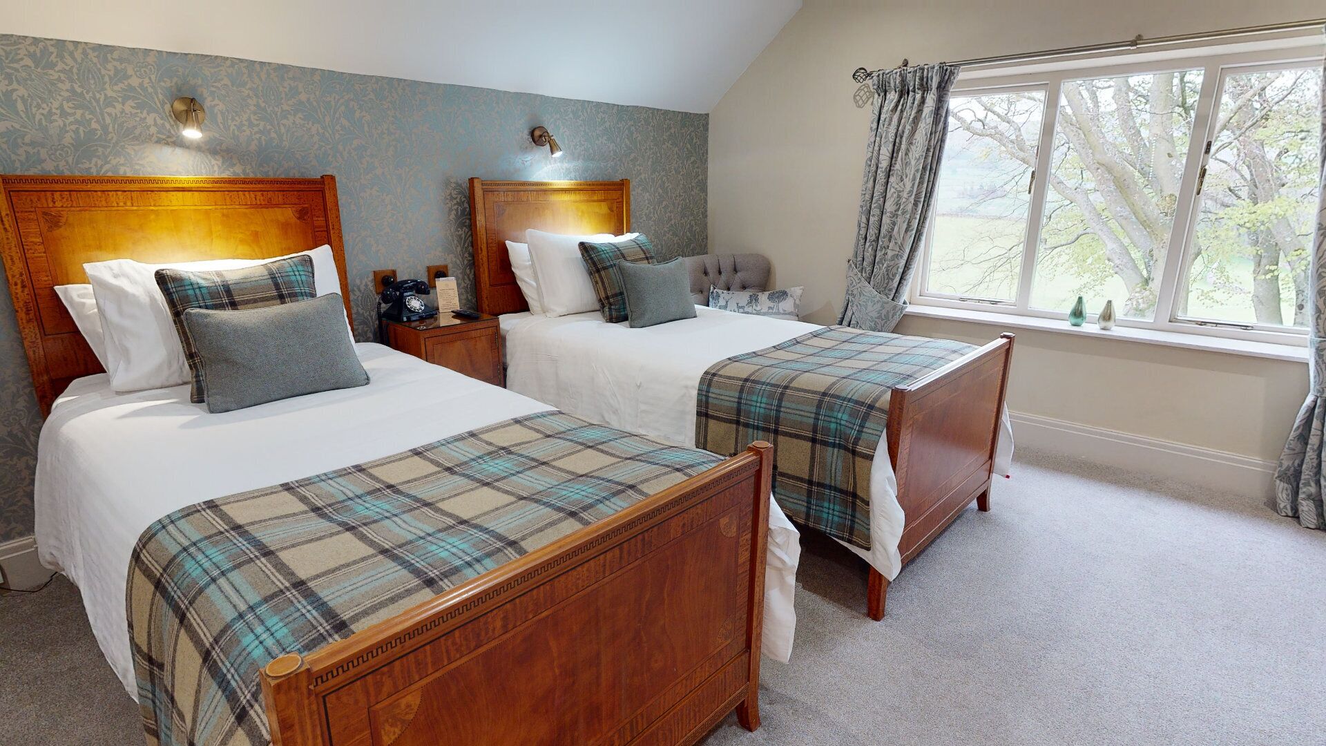 A bedroom with two wooden beds, a nightstand, a telephone, and a window with curtains.