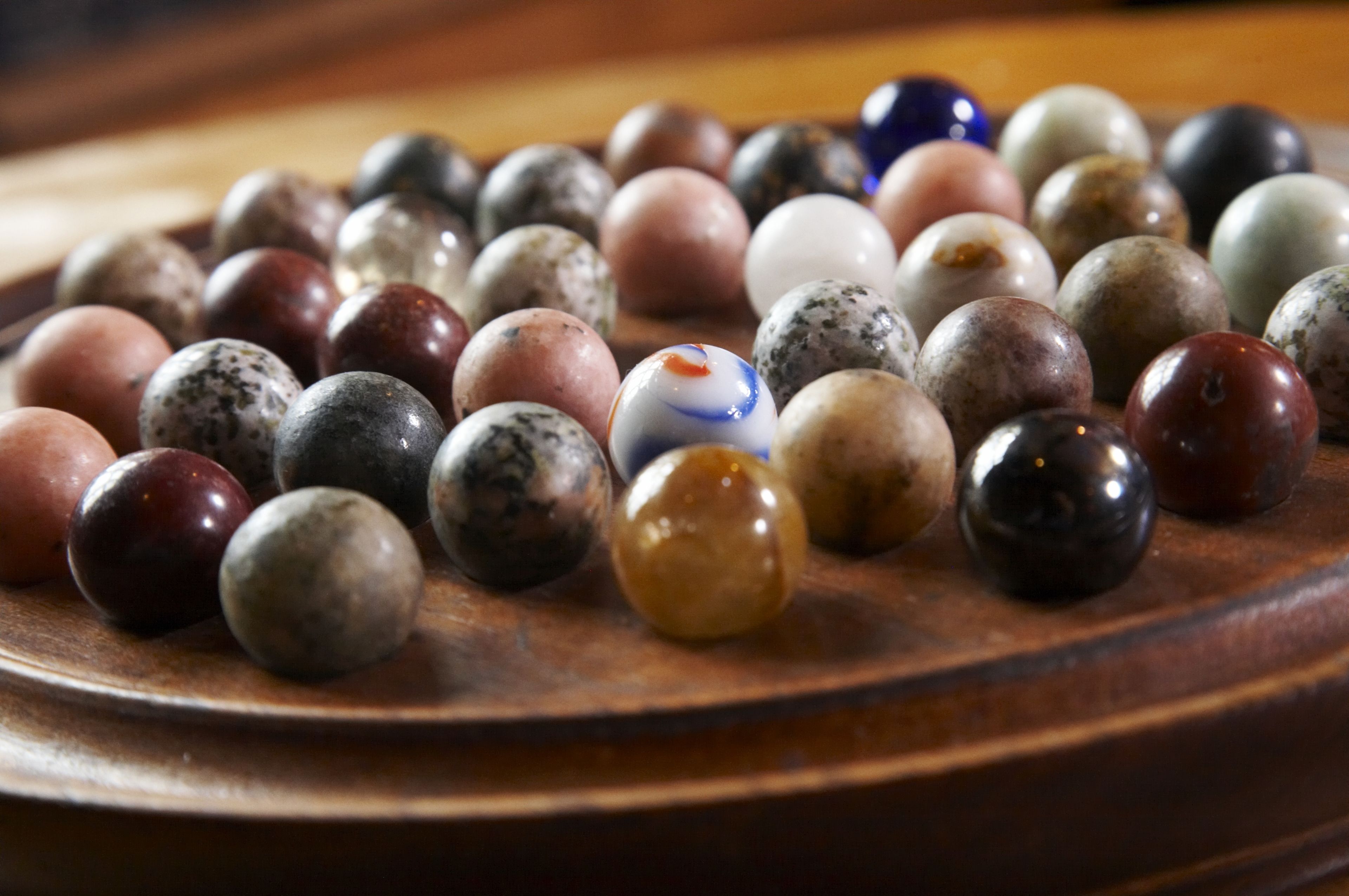 A wooden tray with a variety of marbles.