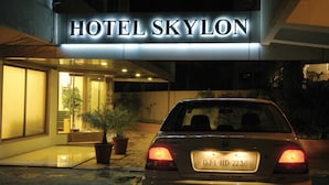 Entrada de un hotel con un letrero que dice "HOTEL SKYLON" y un coche estacionado con una matrícula visible.
