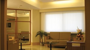 Amplia sala de estar con sofá, mesa de centro, sillas, ventilador de techo y un ventanal con persianas.