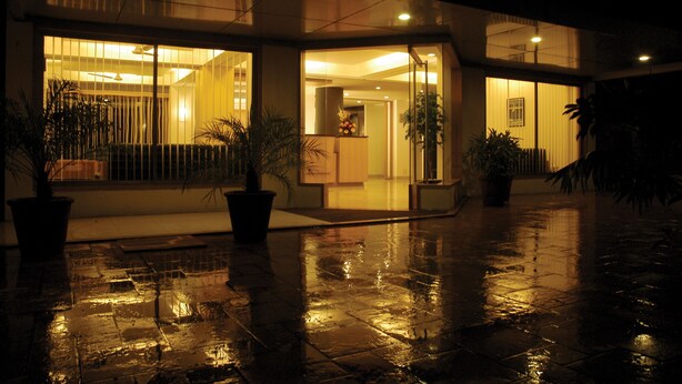 Un edificio moderno con ventanas amplias y pavimento mojado, probablemente un hotel o edificio de oficinas.