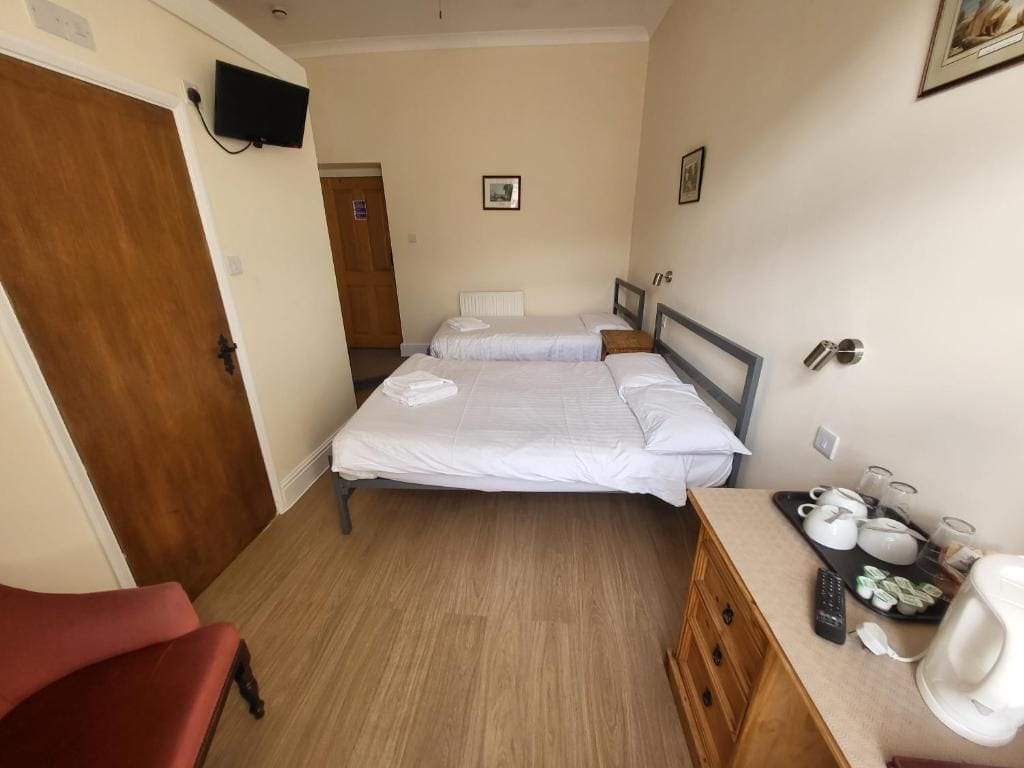 A hotel room with two beds, a wooden dresser, a television, and a coffee maker.