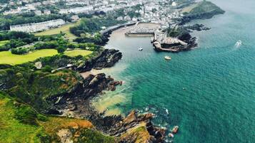 A coastal town with a prominent lighthouse, rocky shoreline, and a clear view of the sea.