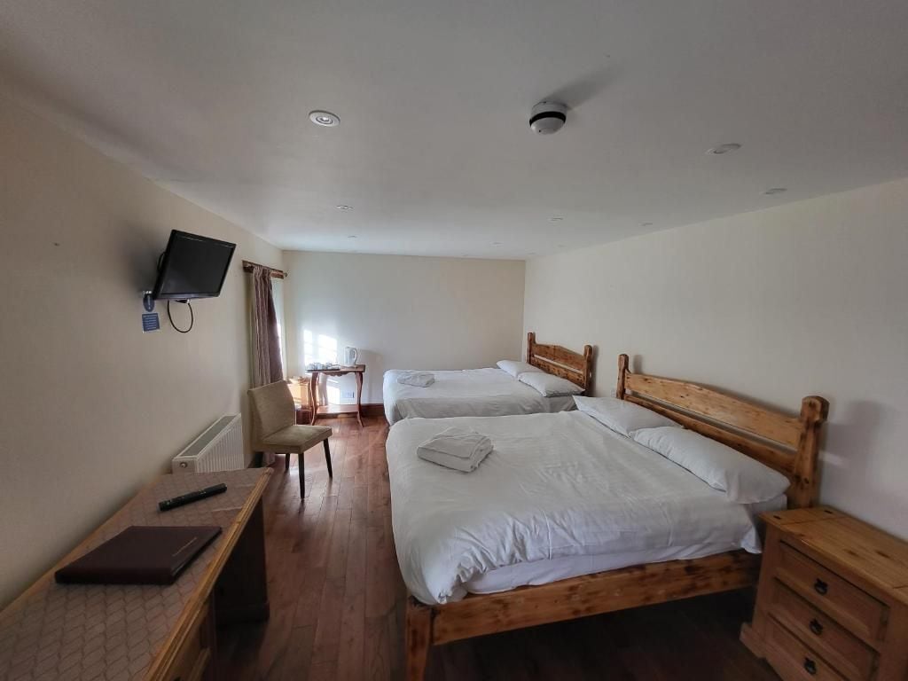 A hotel room with two beds, a desk, a chair, a television, and a window with curtains.