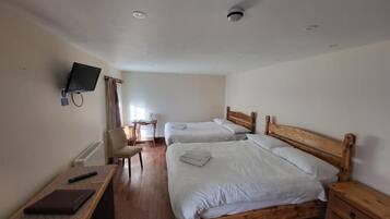 A hotel room with two beds, a desk, a chair, a television, and a window with curtains.