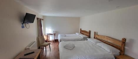Habitación de hotel con dos camas, un escritorio, una silla, un televisor y una ventana con cortinas.