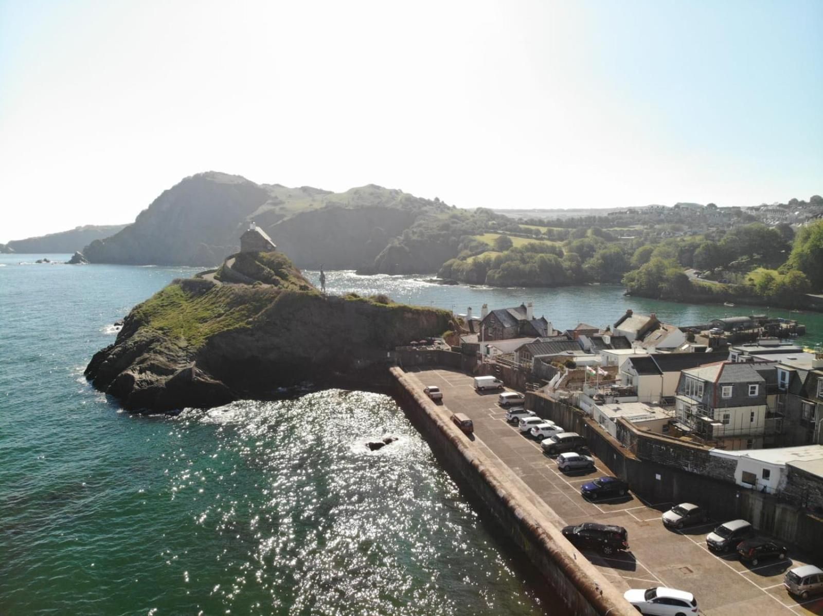 A coastal town with a harbor, buildings, and a rocky outcrop.