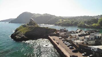 A coastal town with a harbor, buildings, and a rocky outcrop.