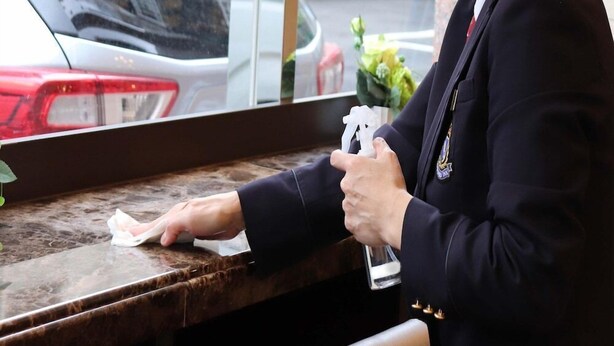 A person in a uniform at a counter, possibly a hotel reception, with a car visible in the background. - Toyoko Inn Kawasaki Ekimae Isago (KANAGAWA)