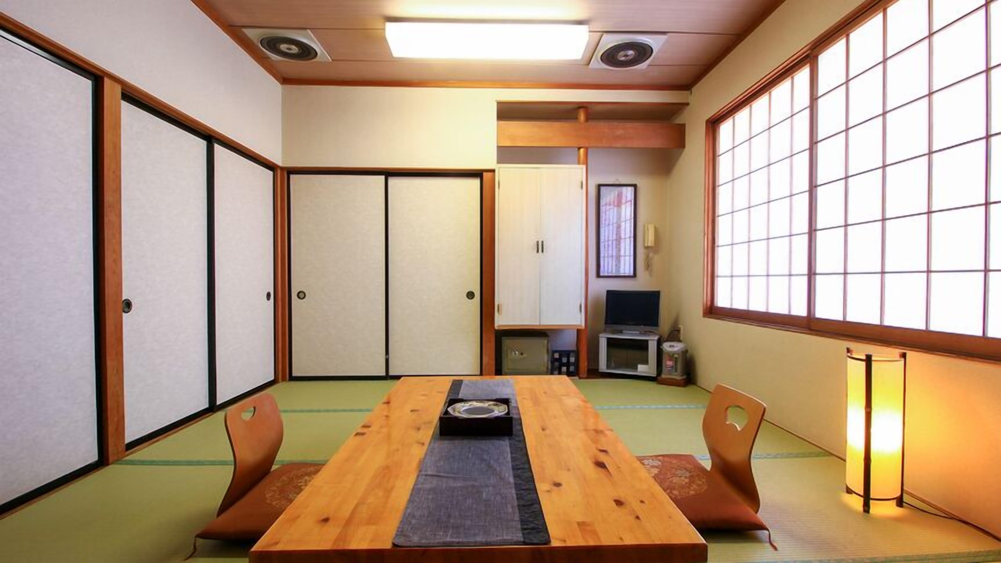 Une pièce de style japonais traditionnel, avec un sol recouvert de tatamis, une petite table basse sur laquelle est posé un plateau, et des portes coulissantes.