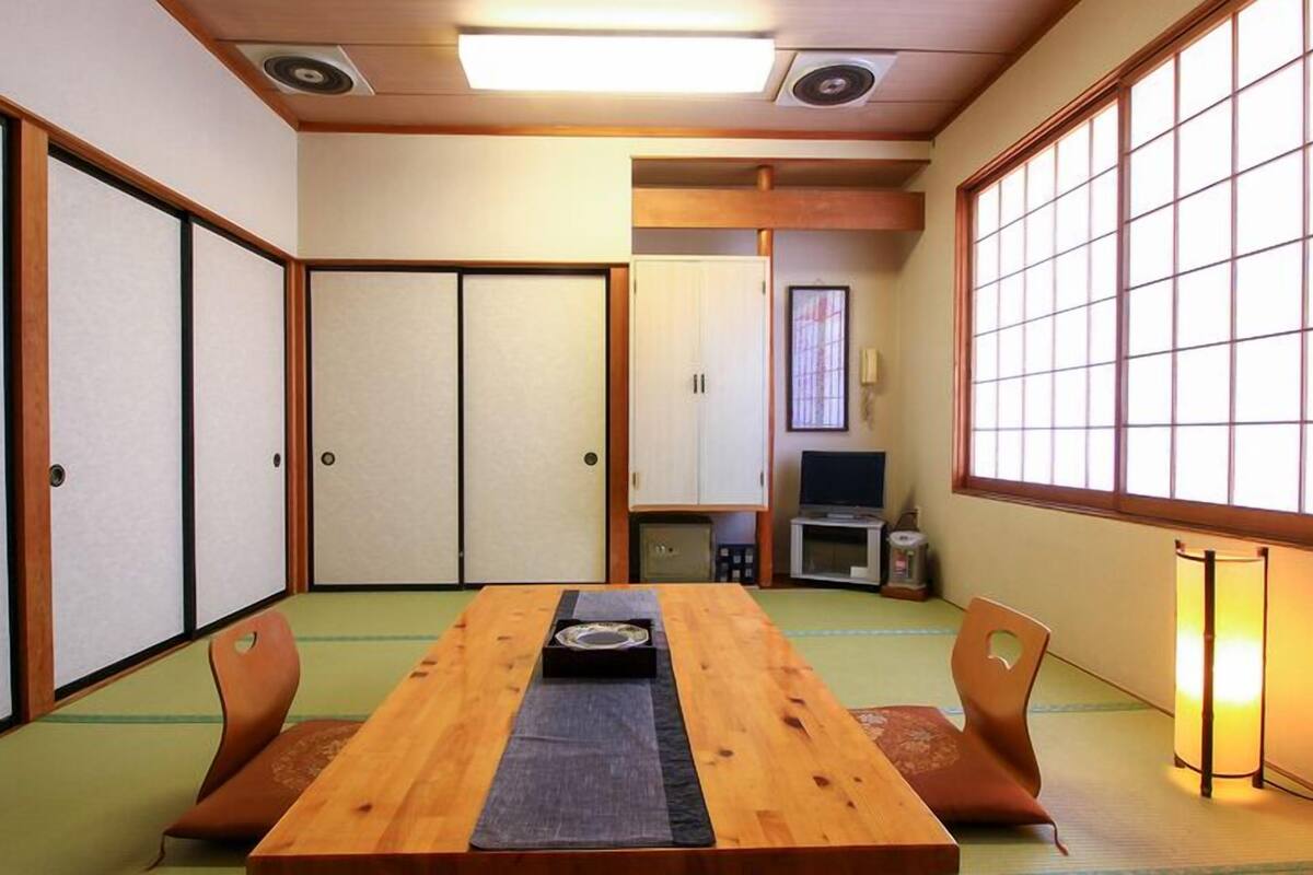 A traditional Japanese-style room with tatami flooring, a low table with a tray, and sliding doors.