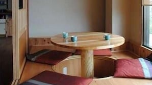 A cozy room with a round wooden table, cushioned seating, and a framed picture on the wall. - Oyado Ichifuji (Nikko)