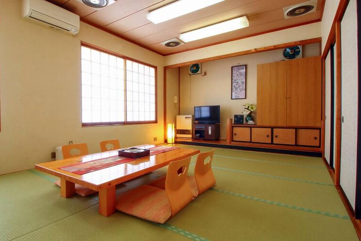 A traditional Japanese room with tatami flooring, a low table, and sliding doors.