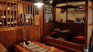 A traditional wooden interior with a low bench, a wooden cabinet with glass doors, and a hanging light fixture. - Oyado Ichifuji (Nikko)